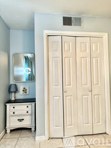 A white wardrobe with a mirror above a dresser in a room.