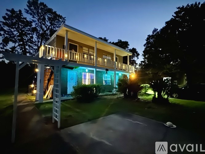 A house with a lit up porch and a white picket fence.
