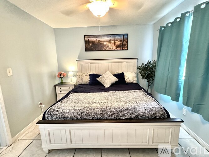 A bedroom with a bed, nightstand, and a painting on the wall.