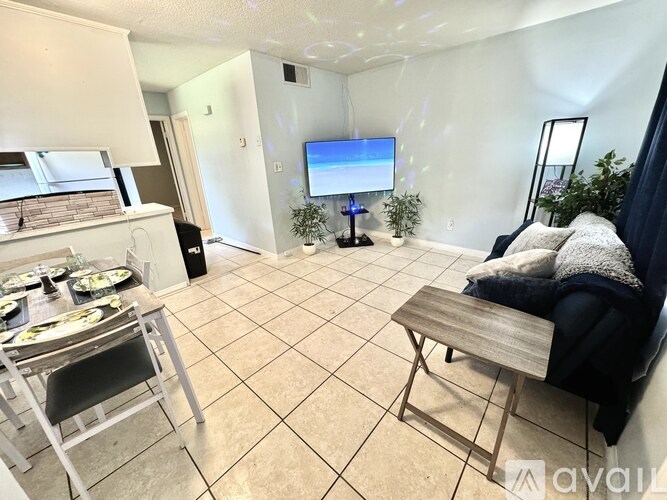 A living room with a TV, a couch, and a dining table.