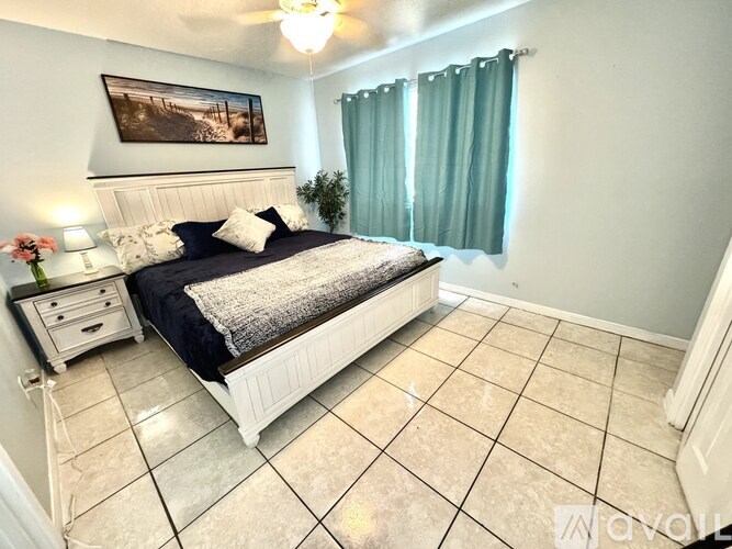 A bedroom with a large bed, nightstand, and a painting on the wall.