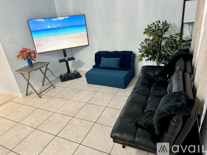 A living room with a blue chair and a black leather sofa.