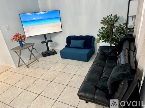 A living room with a blue chair and a black leather sofa.