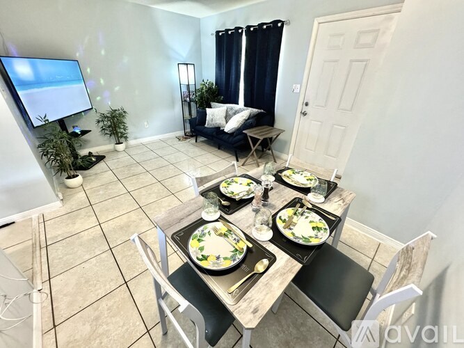 A dining room with a table set for four and a television in the corner.