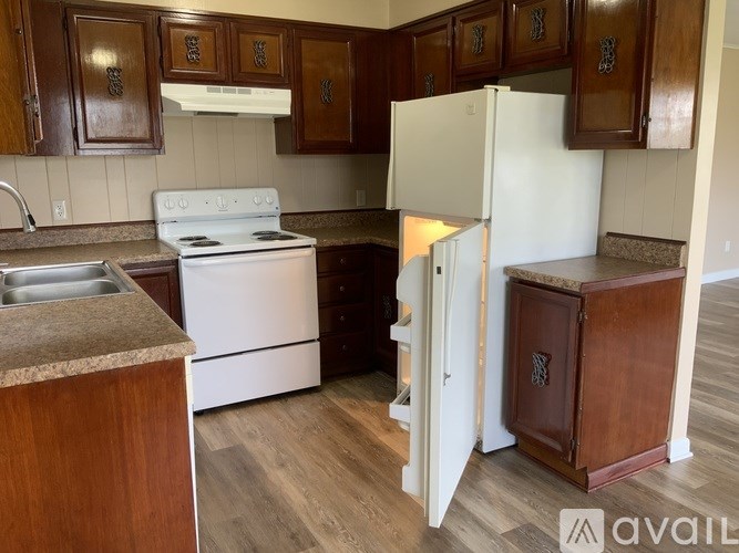 A kitchen with a white stove and wooden cabinets.