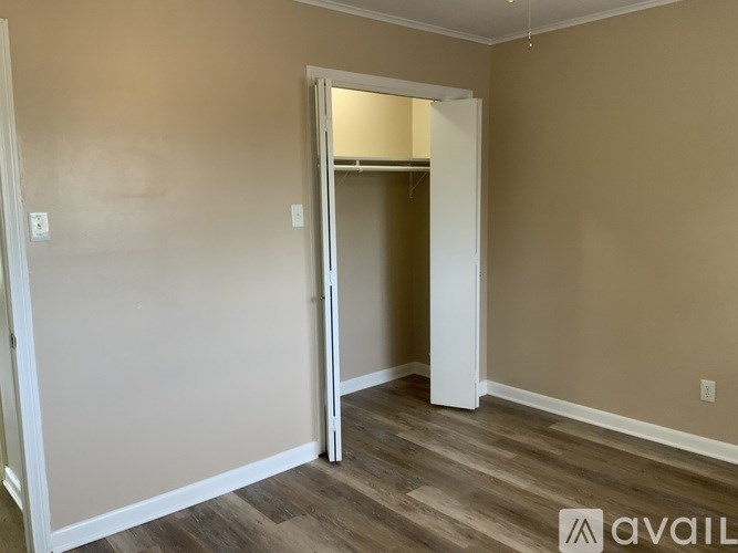 A room with a white door and wooden flooring.
