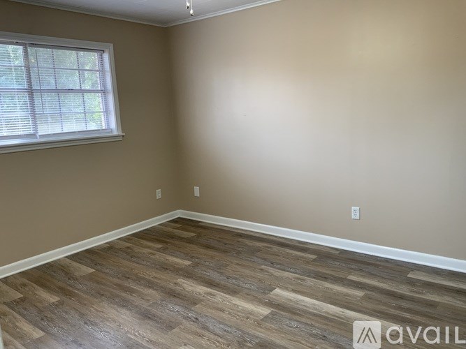A room with wooden flooring and a window with blinds.