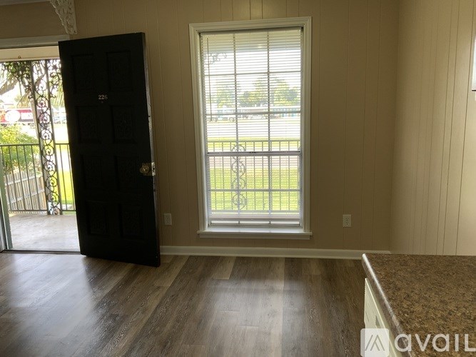 A room with a black door and a window with a view of a fence.