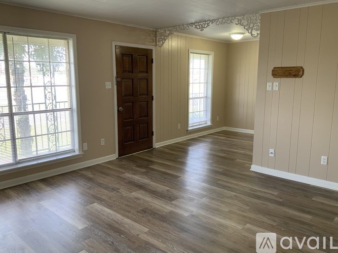 A room with wooden flooring and a brown door.