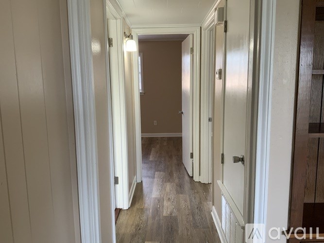 A long hallway with white walls and wood floors.