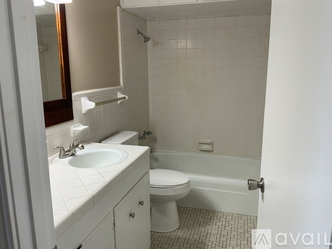 A white bathroom with a toilet, sink, and shower.