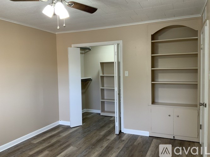 A room with a ceiling fan and built-in shelves.