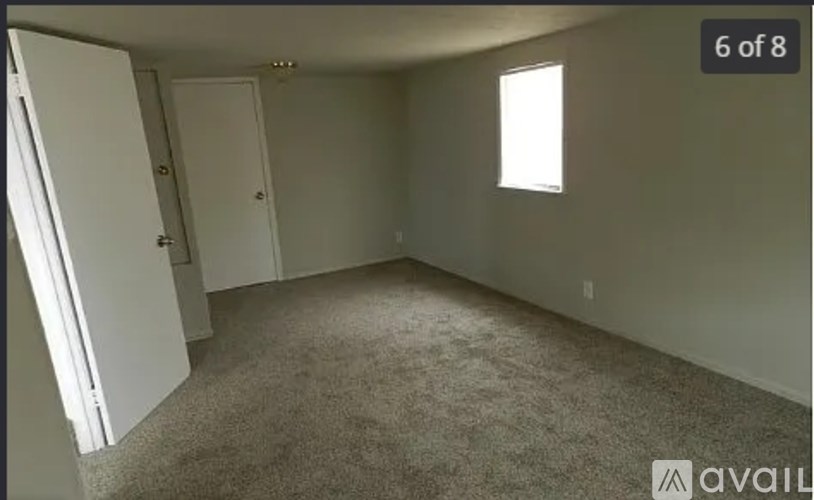 A room with carpeted floor and a window letting in natural light.
