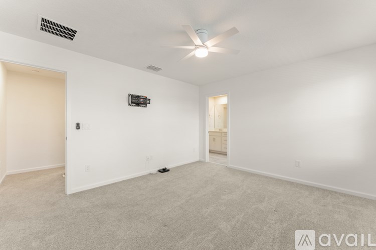 A spacious empty room with a ceiling fan and carpeted floor.