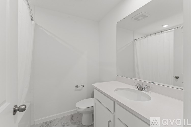 A white bathroom with a toilet, sink, and mirror.