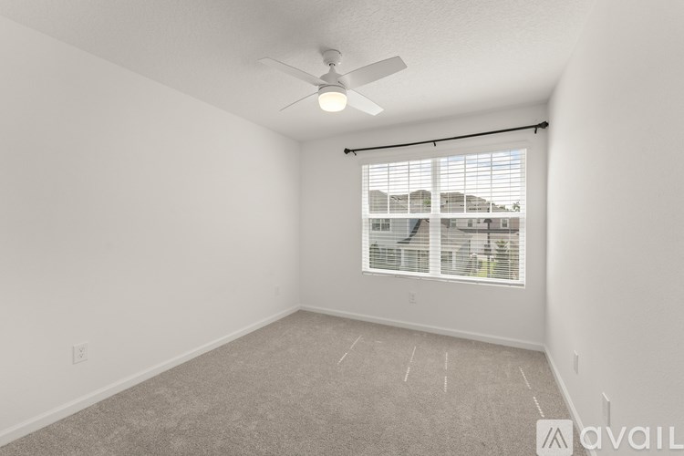 A room with a carpeted floor, a ceiling fan, and a window with blinds.