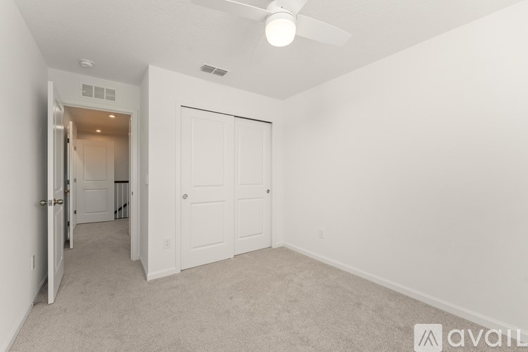 A room with a carpeted floor and a ceiling fan.
