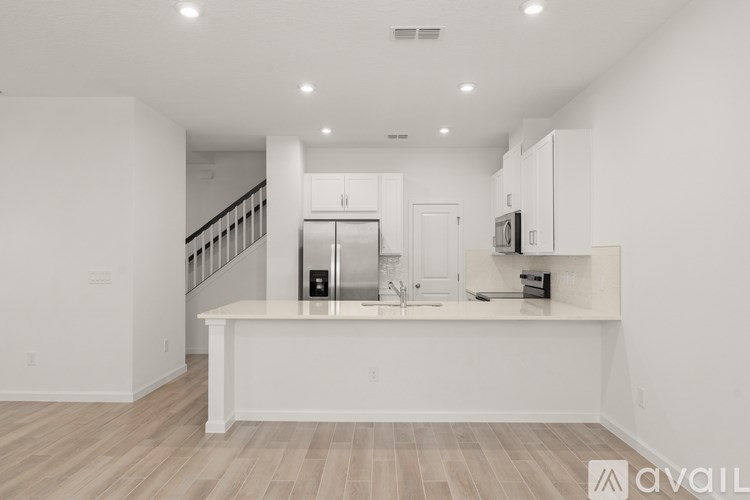 A spacious kitchen with white cabinets and a wooden floor.