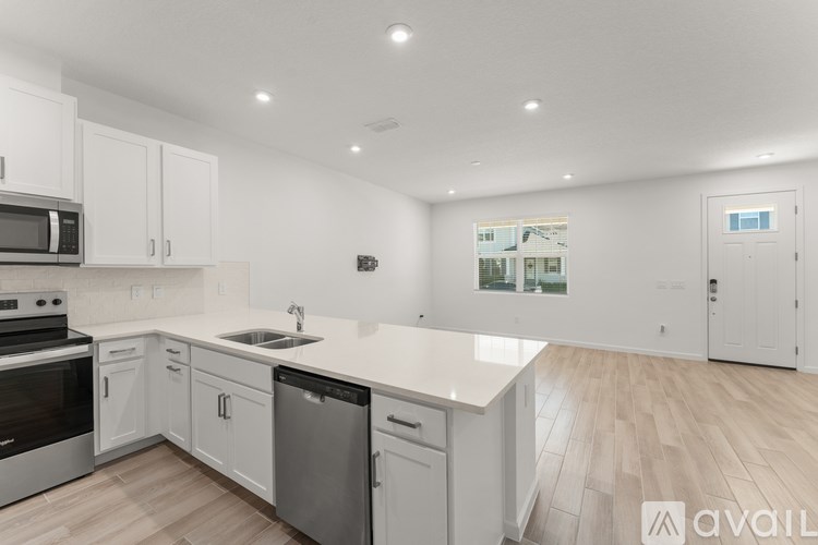 A modern kitchen with white cabinets and a wooden floor.
