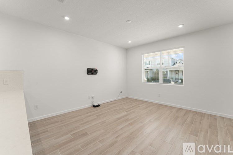 A spacious room with wooden flooring and a large window.