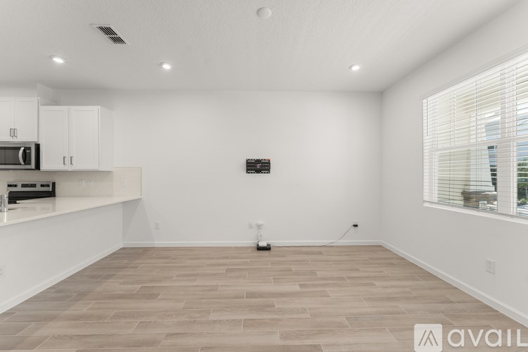 A spacious empty room with wooden flooring and white walls.