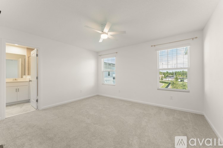 A spacious room with a ceiling fan and a window overlooking a green landscape.