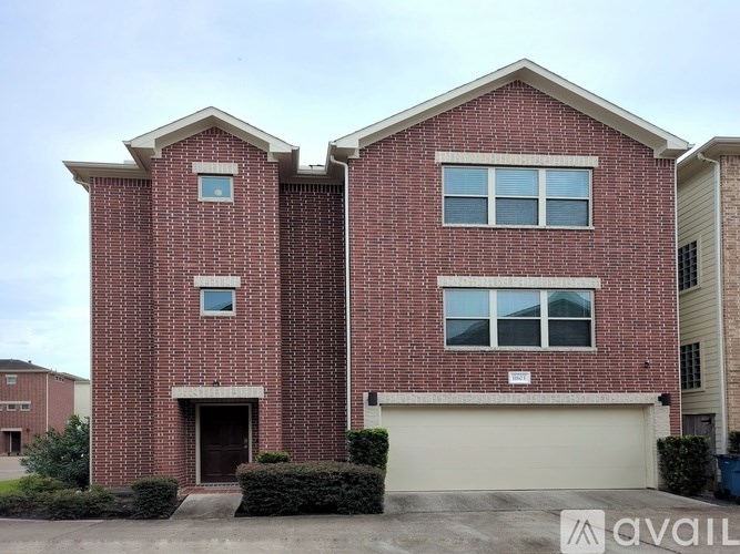 A red brick house with a garage door and a sign that says "AVAILABLE".