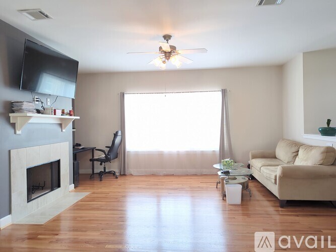 A living room with a fireplace, a couch, a chair, a desk, and a television.