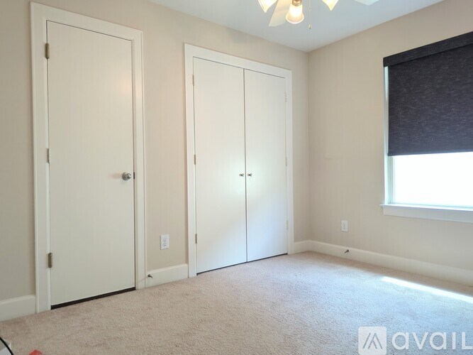 A room with two doors and a window with blinds.