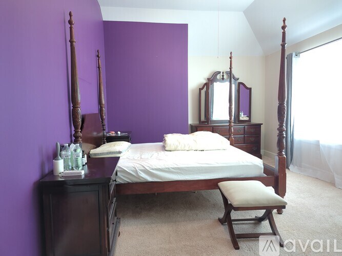 A bedroom with purple walls and a four poster bed.