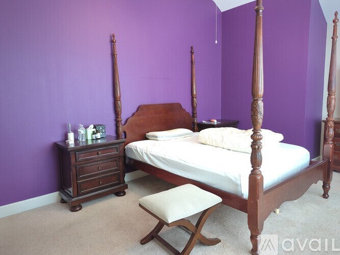 A bedroom with a four poster bed and a bench in front of it.