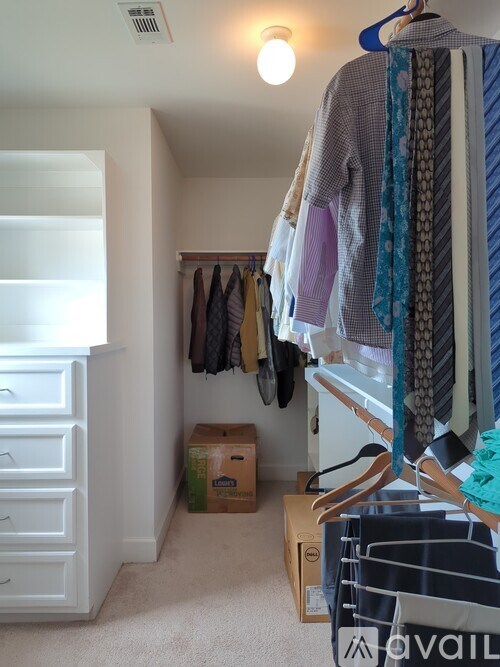 A room with a white wall and a closet with clothes hanging.