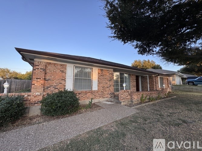A brick house with a gravel driveway in front.