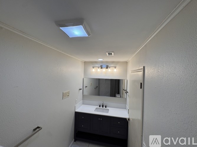 A bathroom with a sink, mirror, and lights.