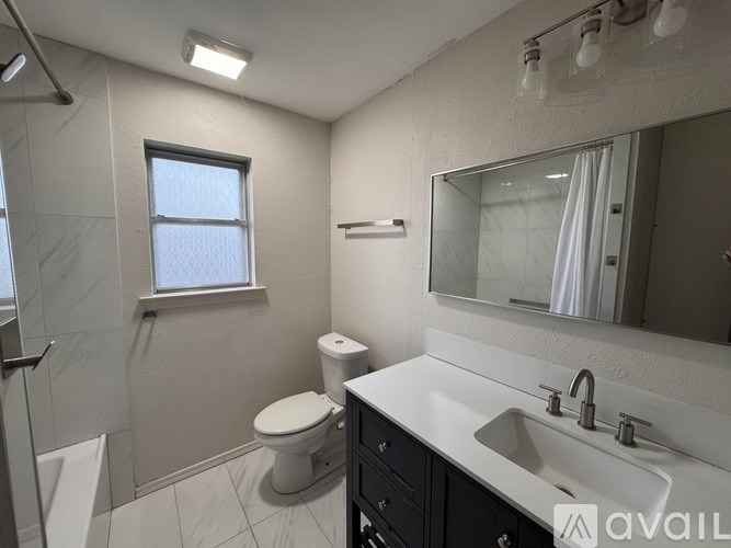 A bathroom with a toilet, sink, and mirror.