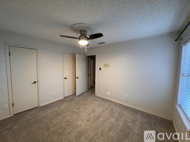 A room with a ceiling fan and carpeted floor.