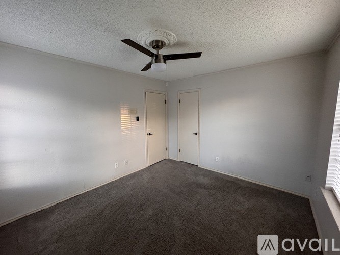 A room with a ceiling fan and two doors.