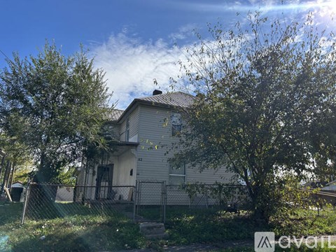 A house with a fence and trees in front of it.