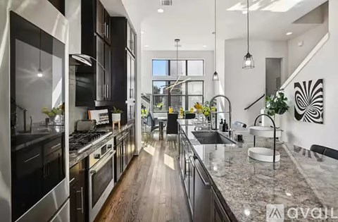 A modern kitchen with black cabinets and stainless steel appliances.