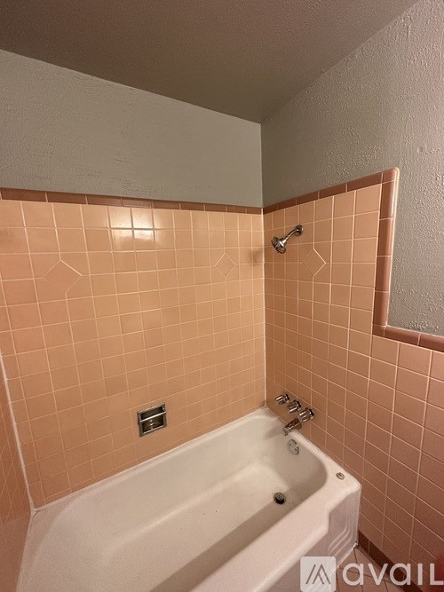 A bathroom with a white tub and pink tiles.