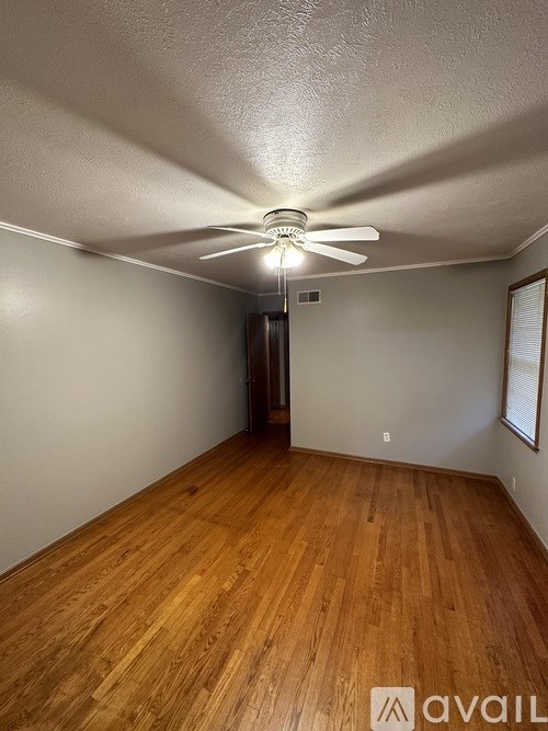 A room with wooden flooring and a ceiling fan.