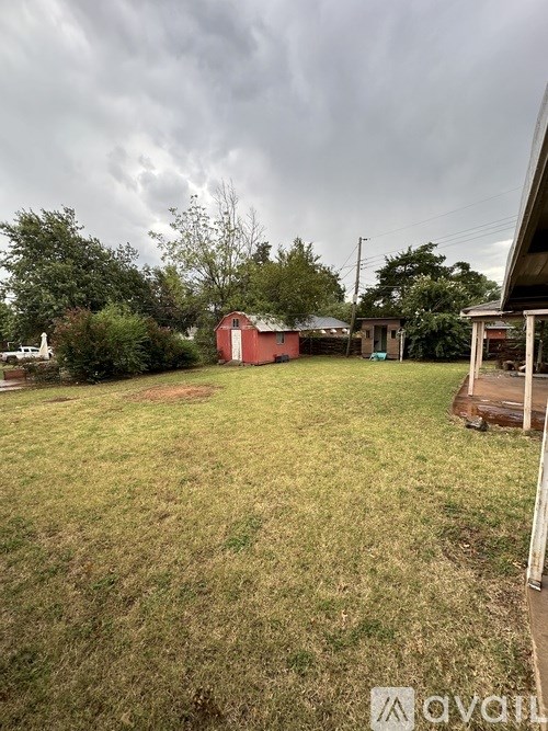 A backyard with a red shed and a wooden fence.