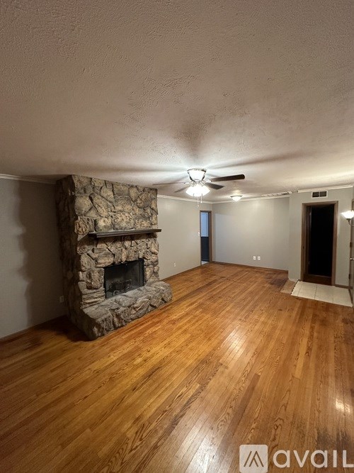 A room with a stone fireplace and wooden flooring.