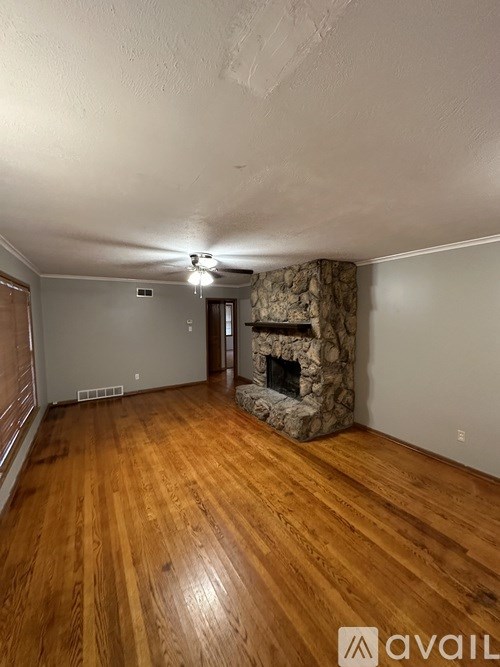 A room with wooden floors and a stone fireplace.