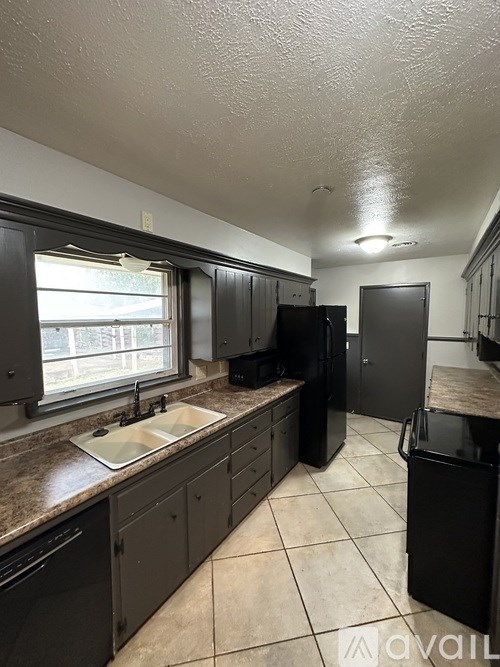 A kitchen with black appliances and brown countertops.