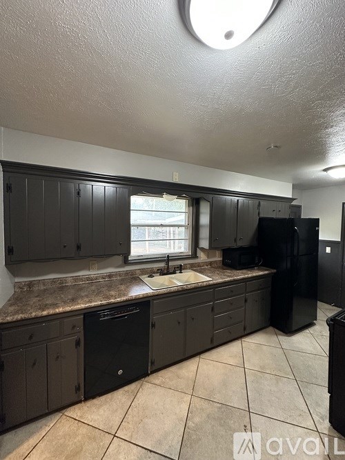A kitchen with black cabinets and a black refrigerator.