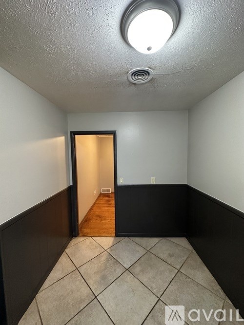 A room with a round ceiling light and a doorway leading to another room.