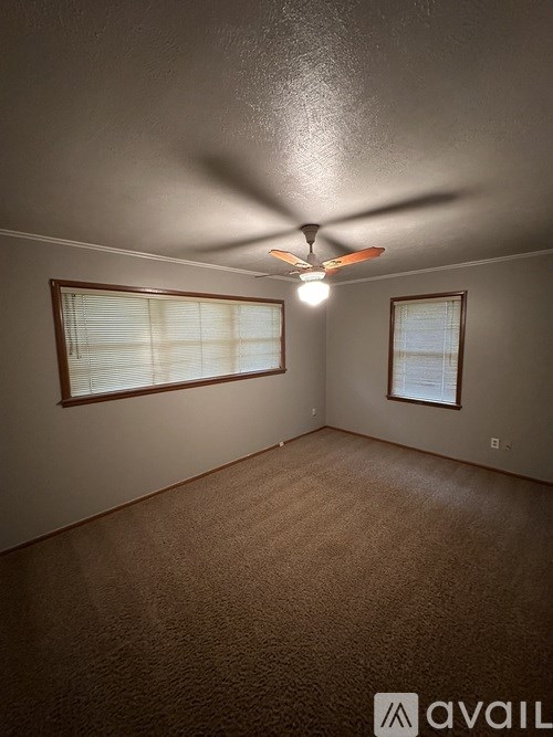 A room with a ceiling fan and two windows.