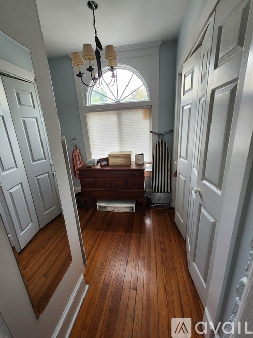 A hallway with a chandelier and a wooden floor.