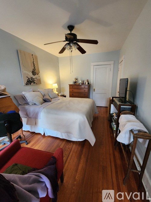 A bedroom with a bed, a chair, and a ceiling fan.